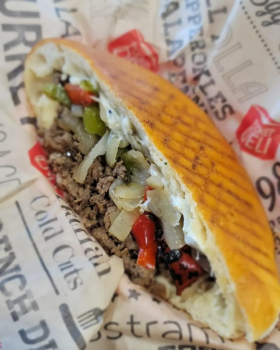 Beef and vegetable sandwich with grilled bread, chopped vegetables, and melted cheese.